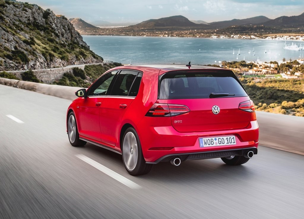 Red Volkswagen Golf GTI driving on a coastal road